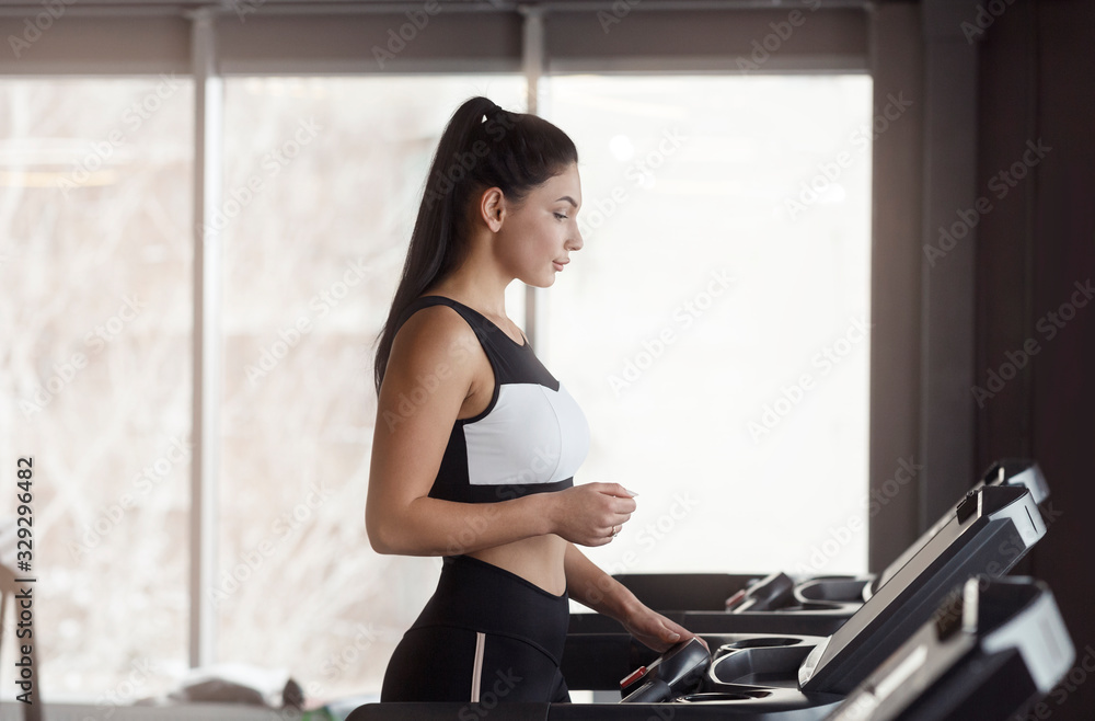 Beautiful Caucasian woman exercising on treadmill in gym, blank space Beautiful Caucasian woman exercising on treadmill in gym, blank space