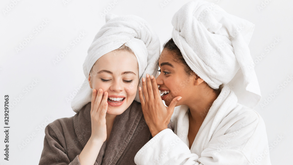 Afro girl in bathrobe sharing secrets with her girlfriend Afro girl in bathrobe sharing secrets with her girlfriend