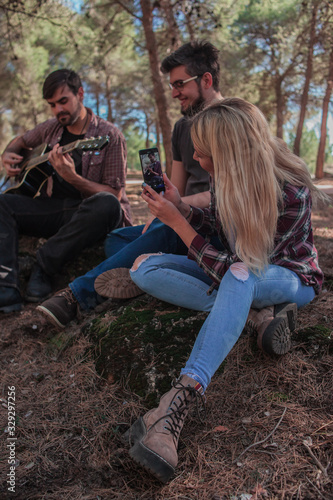 Friends in the field singing and playing a guitar and recording with the mobile phone