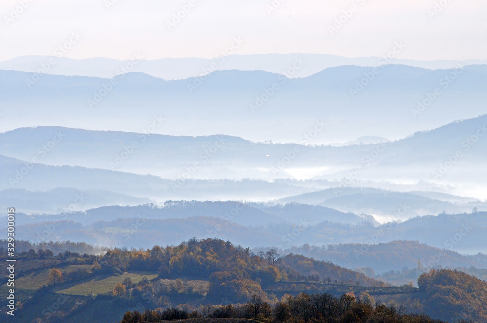 Obraz premium Distant hills in the haze. Beautiful mountain scenery. Mystical rural scenes. Scattered houses of mountain villages. Beautiful nature background.