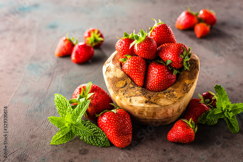 Fresh strawberries in a bowl on wooden table in rustic style