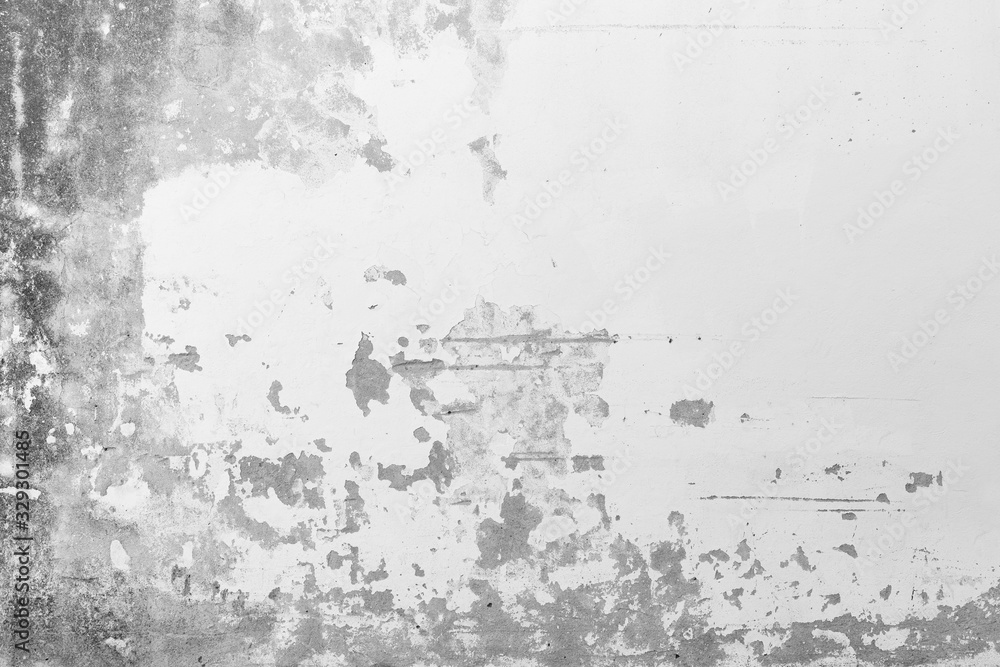 Close-up of a weathered, old and moldy concrete wall, plastering painted in white is broken and peeled off. High resolution abstract full frame textured background in black and white.