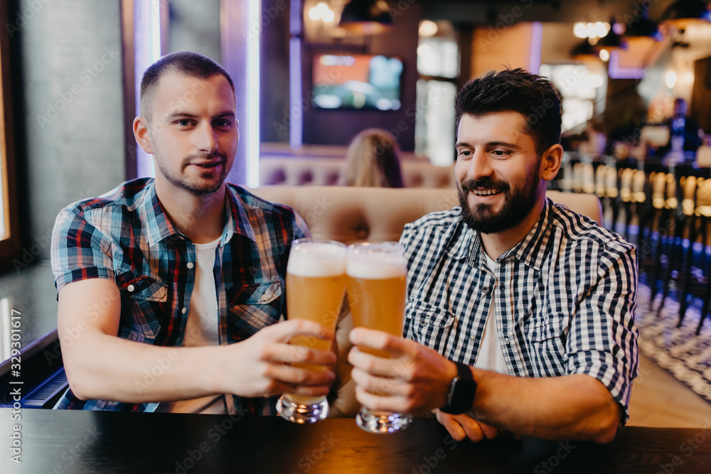 Two mens drinking beer in bar, clinking beer have fun in pub