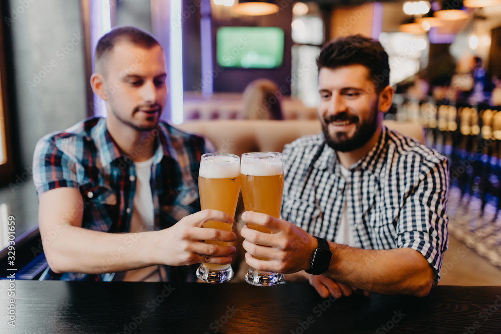 Two mens drinking beer in bar, clinking beer have fun in pub