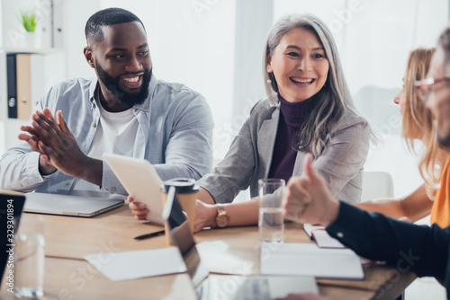 selective focus of smiling multicultural businesspeople talking with their colleagues photo