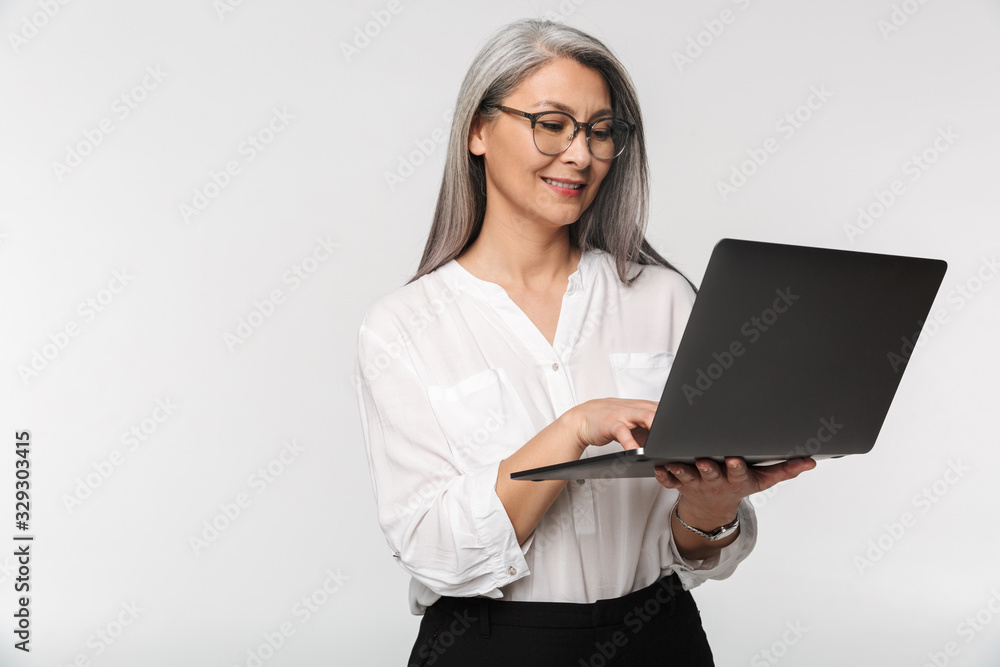 Image of adult mature woman wearing office clothes using laptop computer Image of adult mature woman wearing office clothes using laptop computer