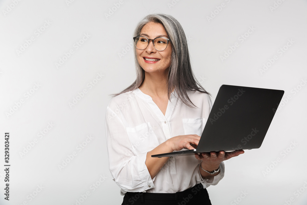 Image of adult mature woman wearing office clothes using laptop computer Image of adult mature woman wearing office clothes using laptop computer