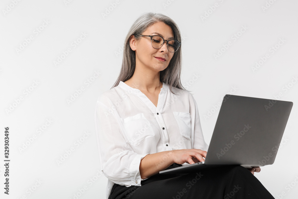 Image of adult mature woman wearing office clothes using laptop computer Image of adult mature woman wearing office clothes using laptop computer