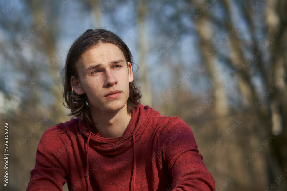 Portrait of a concerned young man sitting in a forest gazing troubled into the distance. Portrait of a concerned young man sitting in a forest gazing troubled into the distance.