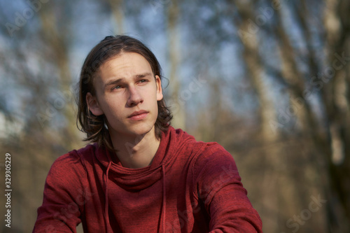 Wallpaper Mural Portrait of a concerned young man sitting in a forest gazing troubled into the distance. Torontodigital.ca