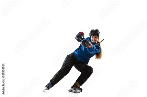 Young female hockey player with the stick on ice court and white background. Sportswoman wearing equipment and helmet training. Concept of sport, healthy lifestyle, motion, action, human emotions.