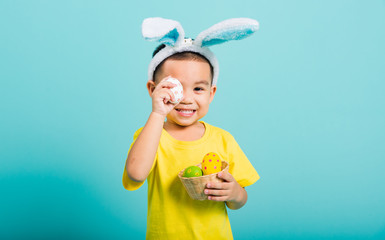 child boy wearing bunny ears and yellow T-shirt, standing to holds easter eggs instead of eyes