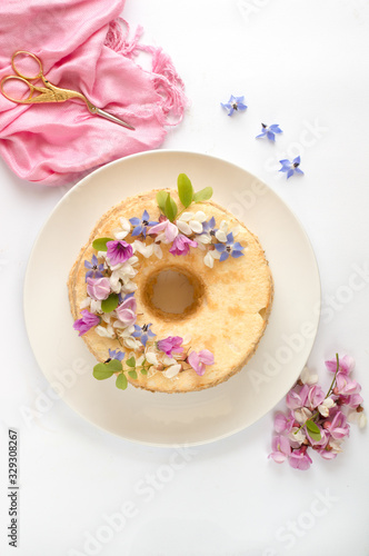 Angel cake su piatto bianco, decorata con fiori e sfondo bianco