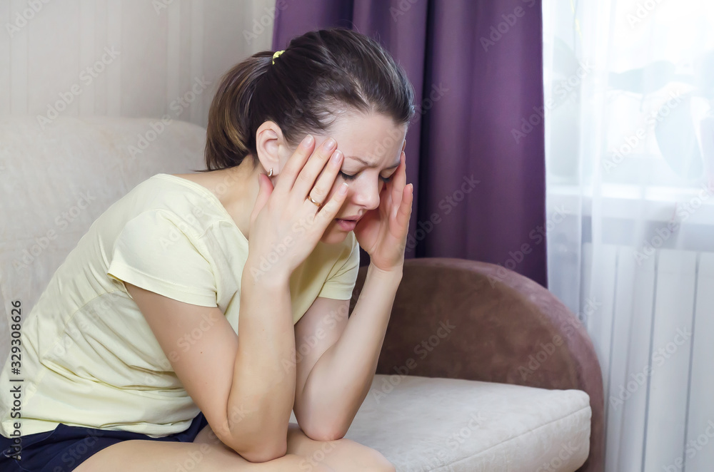 woman holds on to her head. headache in a girl. temperature rise. stress, depression, problems woman holds on to her head. headache in a girl. temperature rise. stress, depression, problems