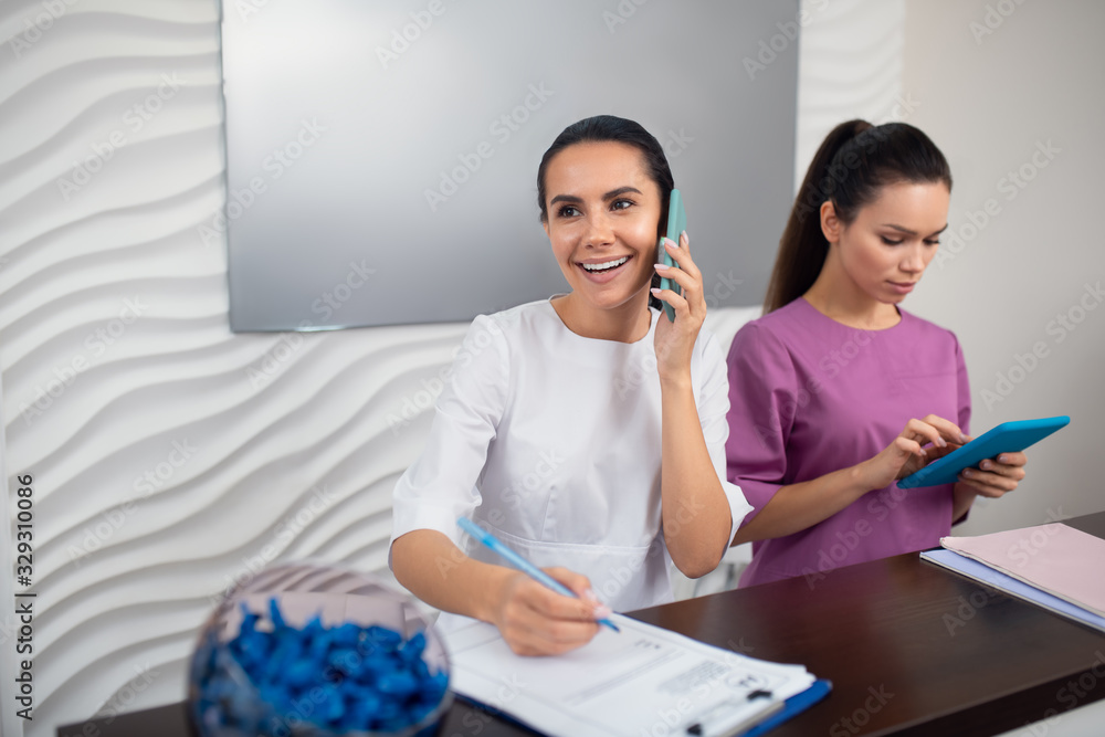 © zinkevych - Receptionist smiling while speaking with client on the phone