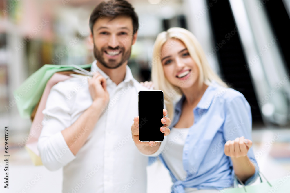 Family Couple Showing Empty Smartphone Screen Standing In Mall Store Family Couple Showing Empty Smartphone Screen Standing In Mall Store