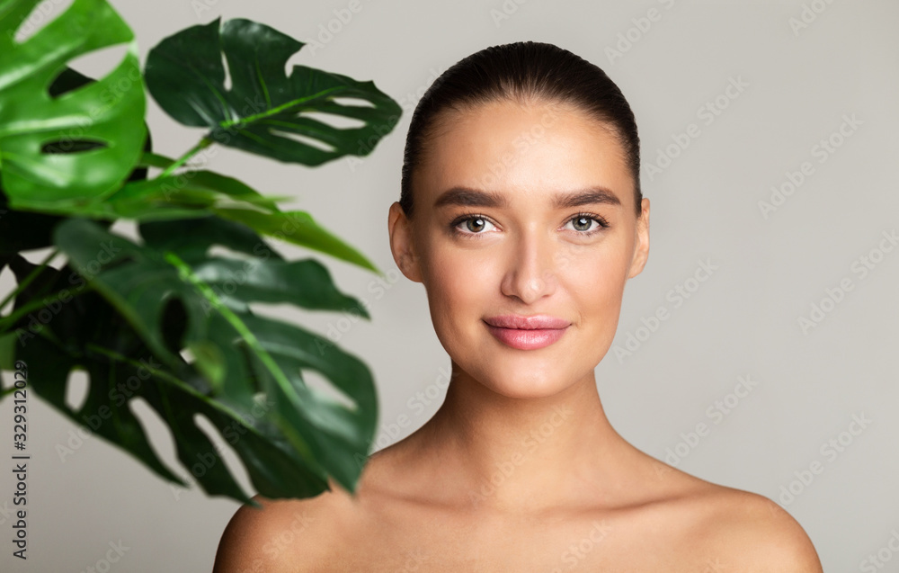 Calm girl with green palm leaf near face Calm girl with green palm leaf near face