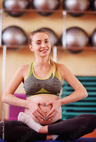 cute young pregnant girl engaged in fitness together with a group of yoga in a sports club