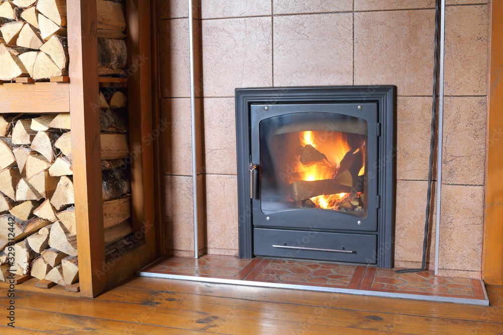 Naklejka premium Fireplace with burning wood in the interior of a rural house.