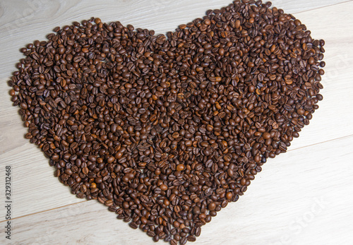 Heart shaped coffee beans on white wooden background © Berna Auyanet