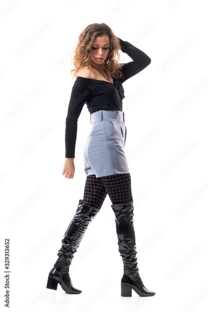 Side view of young class fashionable woman walking and looking down turning back with hand in hair. Full body length isolated on white background. Side view of young class fashionable woman walking and looking down turning back with hand in hair. Full body length isolated on white background.