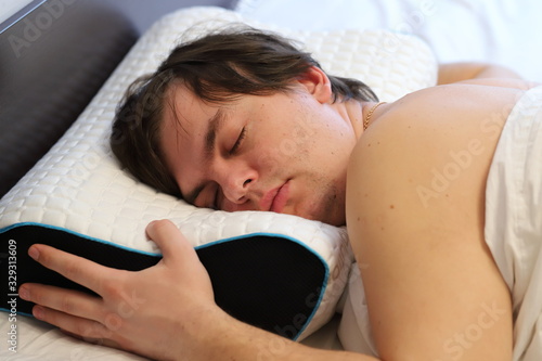 a man sleeps on an orthopedic pillow , a comfortable sleep for health, treatment of osteochondrosis with an orthopedic pillow, back pain.