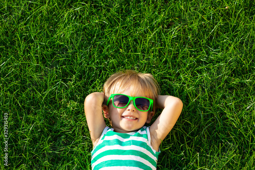 Happy child lying on spring green grass