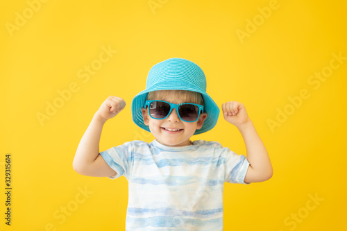Portrait of happy child against yellow background. Summer vacation concept © Sunny studio