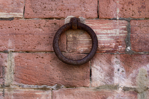 Close up of old rusty iron ring on a red brick wall
