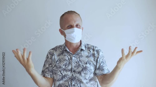 The young man defends himself against the 2020 virus coronavirus and other infections. He sits in a mask and shows bad and displeased emotions about the epidemic.