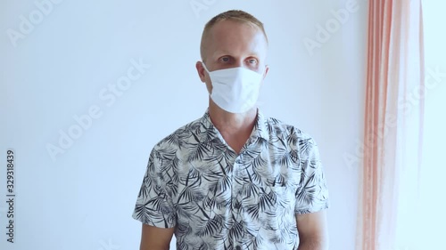 The young man defends himself against the 2020 virus coronavirus and other infections. He sits in a mask and shows bad and displeased emotions about the epidemic.