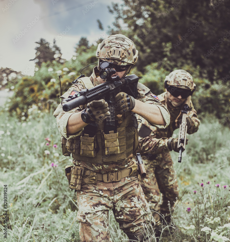 Fototapeta premium Two men in military camouflage vegetato uniforms with automatic assault rifles
