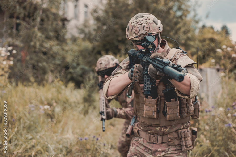 Two men in military camouflage vegetato uniforms with automatic assault rifles Two men in military camouflage vegetato uniforms with automatic assault rifles