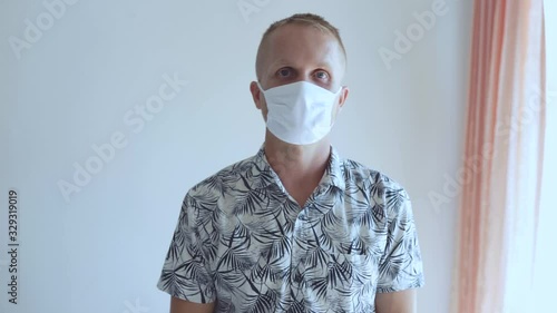 The young man defends himself against the 2020 virus coronavirus and other infections. He sits in a mask and shows bad and displeased emotions about the epidemic.