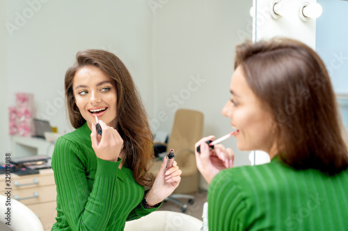 Woman applies lipstick on her lips.
