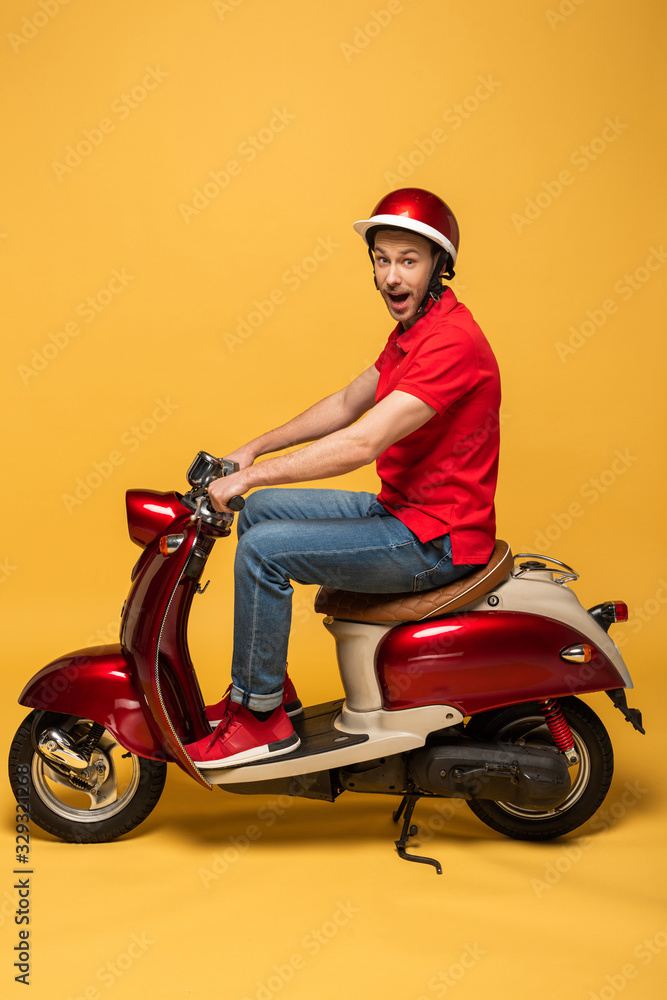 side view of excited delivery man on scooter on yellow background side view of excited delivery man on scooter on yellow background