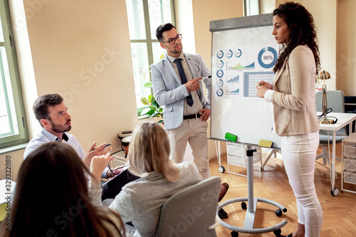 Group of young business people working together in office  two coworker conducting a business presentation using flip chart.