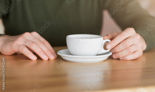 Cropped of guy holding cup of coffee at cafe