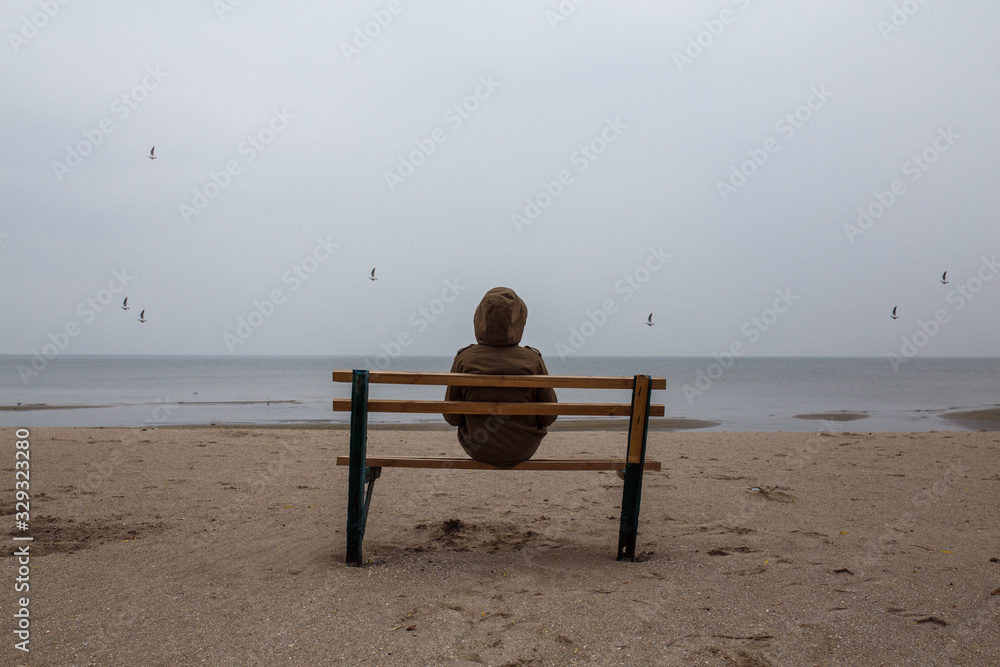 Loneliness human sitting on a bench at the seashore.  Foggy morning at sea.