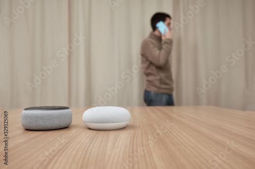 man comparing amazon echo dot, and google nest, with smartphone