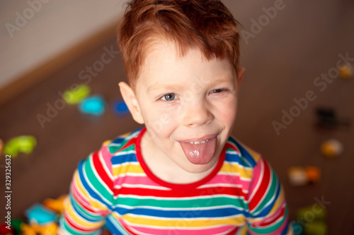 red-haired boy in a multi-colored jacket holds plays in the constructor blocks