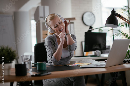 Portrait of businesswoman in office. Beautiful woman listening music at work.