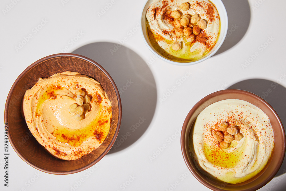 Top view of bowls with hummus and chickpea on grey background