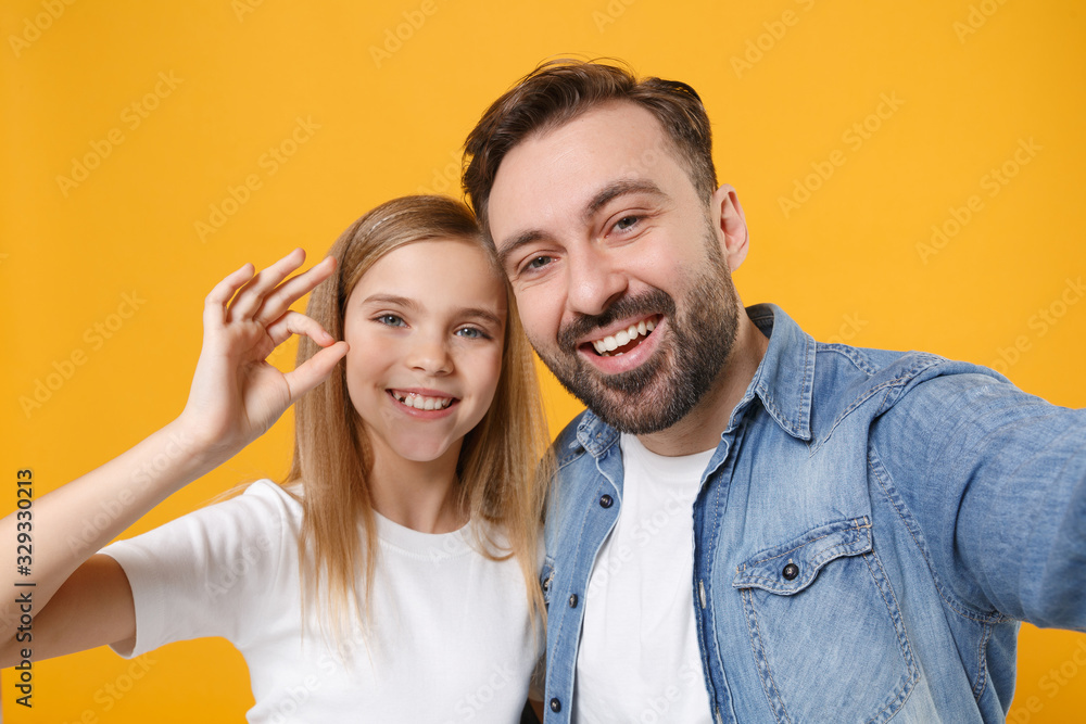 Close up of bearded man with child baby girl. Father little kid daughter isolated on yellow background. Love family day parenthood childhood. Doing selfie shot on mobile phone, showing OK gesture. Close up of bearded man with child baby girl. Father little kid daughter isolated on yellow background. Love family day parenthood childhood. Doing selfie shot on mobile phone, showing OK gesture.