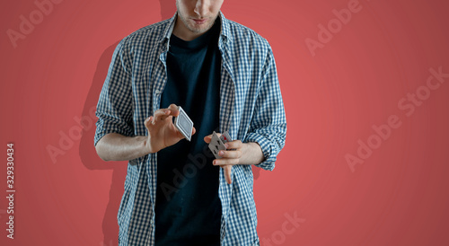 person holding some playing cards and doing the magic trick focus, standing angaist the wall wide webn banner photo