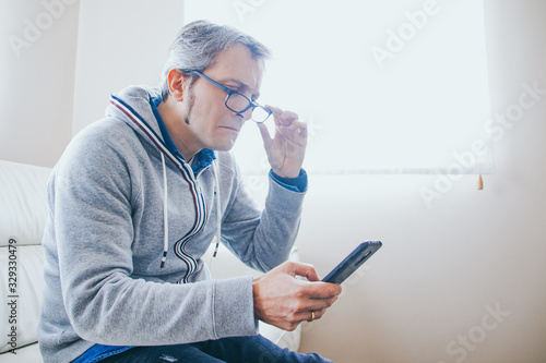 40's man with glasses with presbyopia looking at the phone photo