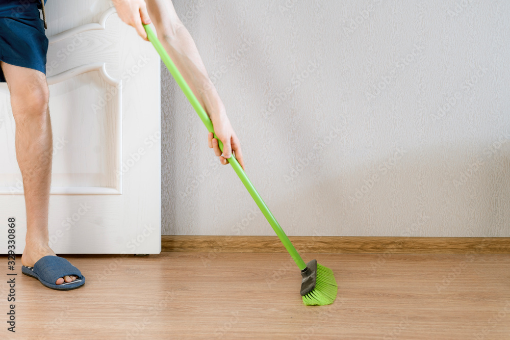 close up person holding a brush and cleaning the floor with a brush at home close up person holding a brush and cleaning the floor with a brush at home