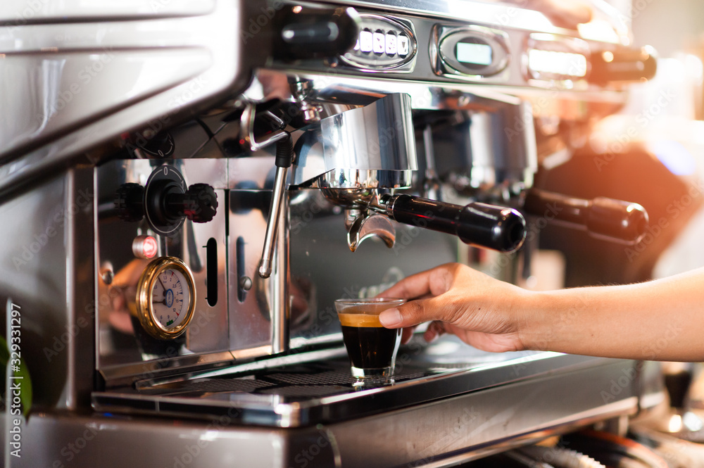 Automatic coffee machines, coffee maker with serving Barista is picking up black coffee to serve to customers. The aroma of fragrant coffee roasted throughout the store. Giving a fresh feeling