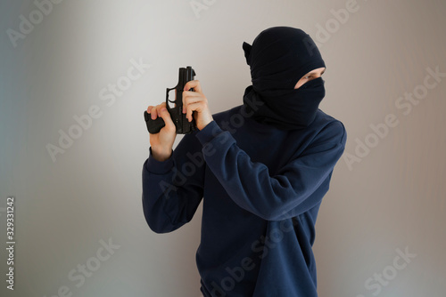 unrecognisable male person in the black mask and pistol, outlaw and crime concept