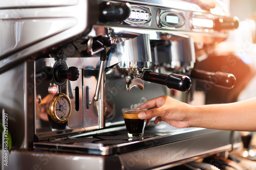 Automatic coffee machines, coffee maker with serving Barista is picking up black coffee to serve to customers. The aroma of fragrant coffee roasted throughout the store. Giving a fresh feeling